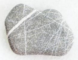 pebble of Greywacke sandstone on white marble photo