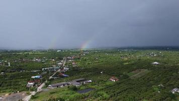 regnbåge i de himmel efter tung regn i de landsbygden. topp se av en flod överfyllda efter tung regn och översvämning av jordbruks fält i lantlig. klimat förändra begrepp. video