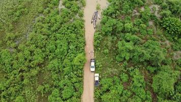 Aerial view of longtail boats in a green meadow is affected by flooding in the rainy season. Top view of the river flowing after heavy rains and flooding of a dirt road that cuts through rural grazing video