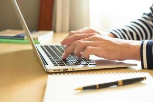 enfoque selectivo en la mano de los hombres asiáticos mientras escribe en el teclado de la computadora y estudia la clase de aprendizaje en línea en casa. concepto de distancia social nuevo estilo de vida normal en el que las personas pueden trabajar o estudiar en casa. foto