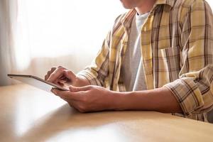 Selective focus at hand and tablet. Indoor shot of men using digital tablet and press the screen for access to apps or studying online at home office, computer device for modern lifestyle. photo