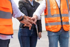 grupo no identificado de trabajadores de varias razas mixtas con un supervisor cogido de la mano para animar y animar antes de trabajar en el sitio de la fábrica industrial. trabajo en equipo, lluvia de ideas laborales o concepto de trabajo en grupo. foto