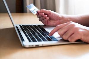 Men hand holding credit card and type payment information on keyboard for order online shopping. Internet technology and Digital market place E-Commerce lifestyle concept, Purchase transaction. photo