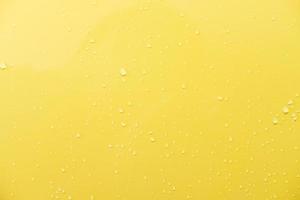 primer plano de la superficie de pintura de coche amarillo brillante. con gota de agua y luz ambiental. concepto de fondo o papel tapiz.