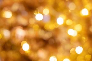 tiro de desenfoque borroso de bokeh de luz de decoración amarilla o dorada. que la gente decora durante el período de celebración navideña. ideal para papel tapiz y fondo. foto