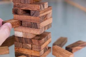 Selective focus at wood brick. Business people using hand to pull out wood brick with caution. taking risk and make decision to play the game. Insurance or financial risk management and safety concept photo