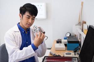 enfoque selectivo en el marco del sendero de optometría. médico optometrista asiático que usa equipo de gafas de rastro para examinar el sistema visual de la vista del paciente para resolver el problema de la visión. foto