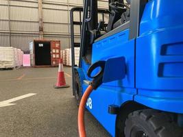 Electrical forklift vehicle park and plug in for charging battery inside of logistic warehouse. Alternative energy source for car and machine in industrial business segment. Automotive technology. photo