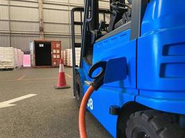Electrical forklift vehicle park and plug in for charging battery inside of logistic warehouse. Alternative energy source for car and machine in industrial business segment. Automotive technology. photo