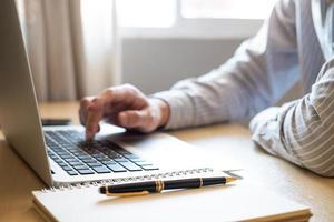 enfoque selectivo en la mano de los hombres asiáticos mientras escribe en el teclado de la computadora y estudia la clase de aprendizaje en línea en casa. concepto de distancia social nuevo estilo de vida normal en el que las personas pueden trabajar o estudiar en casa. foto