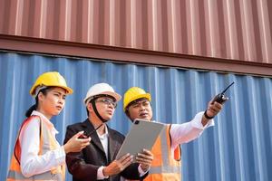 Selective focus at face Asian men worker. industrial warehouse container worker wearing safety workwear and taking with their supervisor while record data online with digital connection tablet. photo