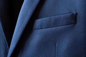 High resolution with details and quality shot of formal dark blue wool suit fabric texture. with front pocket decoration under light and shadow ambient. Ideal for background or wallpaper. photo