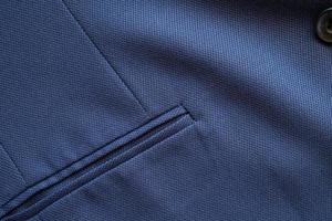 alta resolución con detalles y toma de calidad de textura formal de tela de traje de lana azul oscuro. con decoración de bolsillo frontal bajo ambiente de luz y sombra. ideal para fondo o papel tapiz. foto