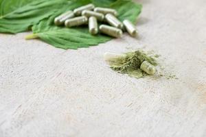 Selective focus at herbal powder. with blurred herb capsule with herbal leaf on natural wooden background with copy space. Alternative medicine that can cure illness without using drug photo