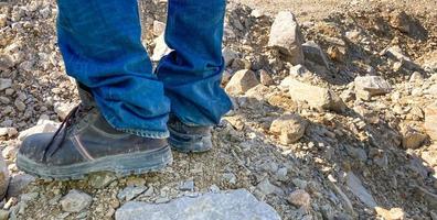 una pancarta horizontal de hombres que usan botas industriales de trabajo pesado parados en la roca dentro de la mina industrial. ropa de trabajo duradera para condiciones de trabajo duras para protección y seguridad foto