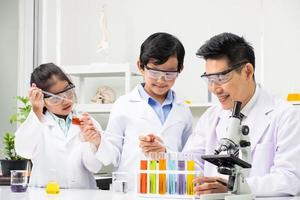 Selective focus at face. Young Asian boy and girl smile and having fun while doing science experiment in laboratory classroom with Teacher. Study with scientific equipment and tubes. Education concept photo