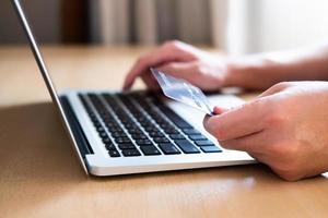 los hombres sostienen la tarjeta de crédito y escriben la información de pago en el teclado para ordenar compras en línea. tecnología de Internet y concepto de estilo de vida de comercio electrónico de mercado digital, transacción de compra. foto