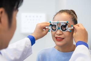 enfoque selectivo en la cara de las mujeres. mientras que el médico usa equipo de optometría y marco de anteojos de prueba para examinar el sistema visual de las mujeres mayores con máquina y técnica profesional. foto