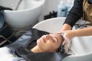 Beautiful Caucasian women feel relax and comfortable while getting hair wash with shampoo and massage. Hair salon studio with hair stylish, beauty and fashion concept. photo