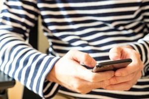 enfoque selectivo en el teléfono inteligente. hombres con ropa informal escribiendo texto o enviando mensajes cortos desde un dispositivo móvil. concepto de tecnología de comunicación de banda ancha inalámbrica o de Internet. foto