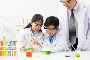 jóvenes estudiantes asiáticos que usan google protector mientras estudian y hacen experimentos científicos en el aula con el maestro. momento de aprendizaje y diversión. concepto de aula de química o biología. foto