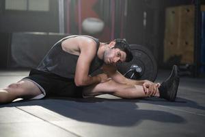 los hombres caucásicos adultos guapos se calientan y estiran antes de hacer ejercicio cruzado dentro del gimnasio para entrenar la fuerza corporal y los músculos firmes de los brazos y la buena salud física del cuerpo. foto