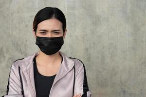 enfoque selectivo en la cara de jóvenes hermosas mujeres asiáticas que usan mascarilla quirúrgica con emoción seria o estresante antes de hacer ejercicio o correr en el parque de la ciudad por la mañana. nuevo estilo de vida normal. foto