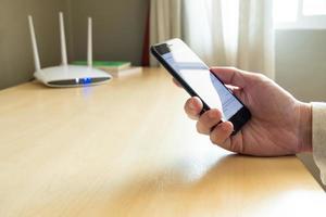 Men hand using smartphone device to connect to wifi network from internet router. Broadband high speed internet network technology for access to many application and services online. photo