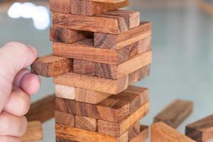 Selective focus at wood brick. Business people using hand to pull out wood brick with caution. taking risk and make decision to play the game. Insurance or financial risk management and safety concept photo