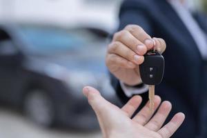 el vendedor lleva las llaves del auto entregadas al cliente en la sala de exposición con una oferta de bajo interés. promoción especial foto