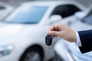 Salesman is carrying the car keys delivered to the customer at the showroom with a low interest offer. Special promotion photo