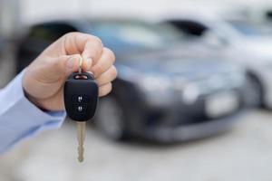 Salesman is carrying the car keys delivered to the customer at the showroom with a low interest offer. Special promotion photo