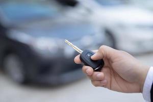 Salesman is carrying the car keys delivered to the customer at the showroom with a low interest offer. Special promotion photo