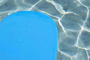 Blue kickboard floating on swimming pool water surface. photo