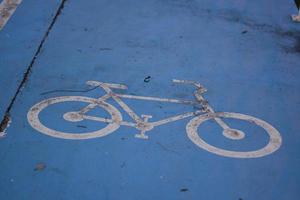 On the street painted bike path in the park. Bicycle lane sign on blue asphalt. photo