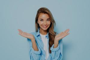 Optimistic lovely young female spreads hands, smiles happily photo