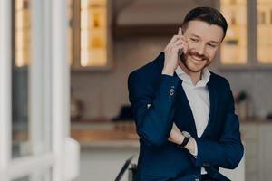 Happy executive director in stylish suit and with phone indoors photo