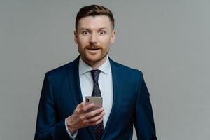 Amazed businessman in suit reading good news on smartphone photo