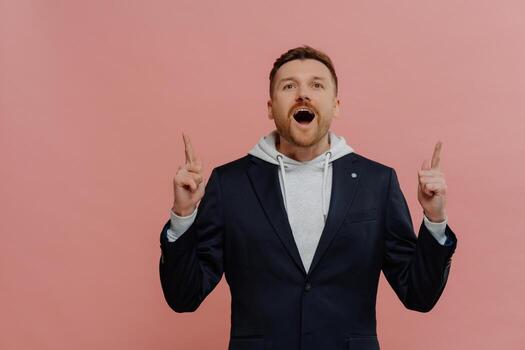 Amazed ginger man pointing up with index fingers and excited face expression photo