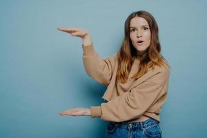 Surprised female showing big large size with hands photo