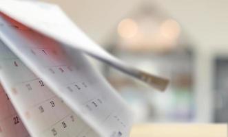 Close up white paper desk calendar with blurred bokeh background appointment and business meeting concept photo