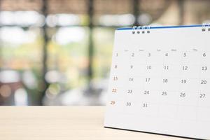 white paper desk calendar on wood table with blurred bokeh background appointment and business meeting concept photo