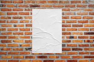 Blank white wheatpaste glued paper poster mockup on brick wall background photo