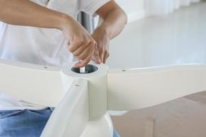 Asian man assembling white table furniture at home photo