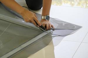 man install mosquito net wire screen on house window protection against insect photo