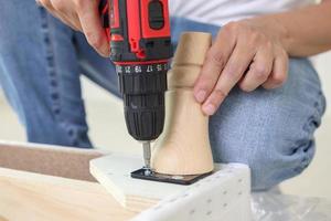 man assembling sofa furniture at home using cordless screwdriver photo