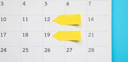Blank yellow sticky adhesive post note paper planner with space on calendar page background for business planning appointment meeting concept photo