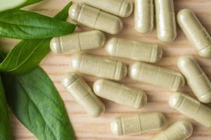 Herbal medicine capsules with Andrographis paniculata leaf on wood table photo