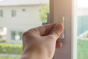 Hand hold mosquito net wire screen handle on house window photo