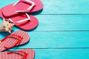 Summer flip flops with shell and copy space on blue wooden background. Top view. Summertime. Fun weekend holidays photo